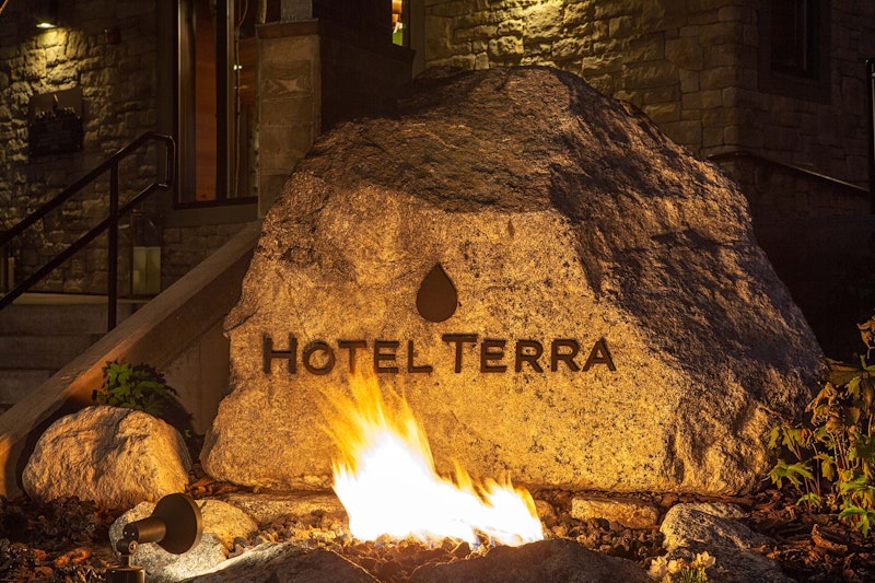 Rock that says "Hotel Terra" with fire in front