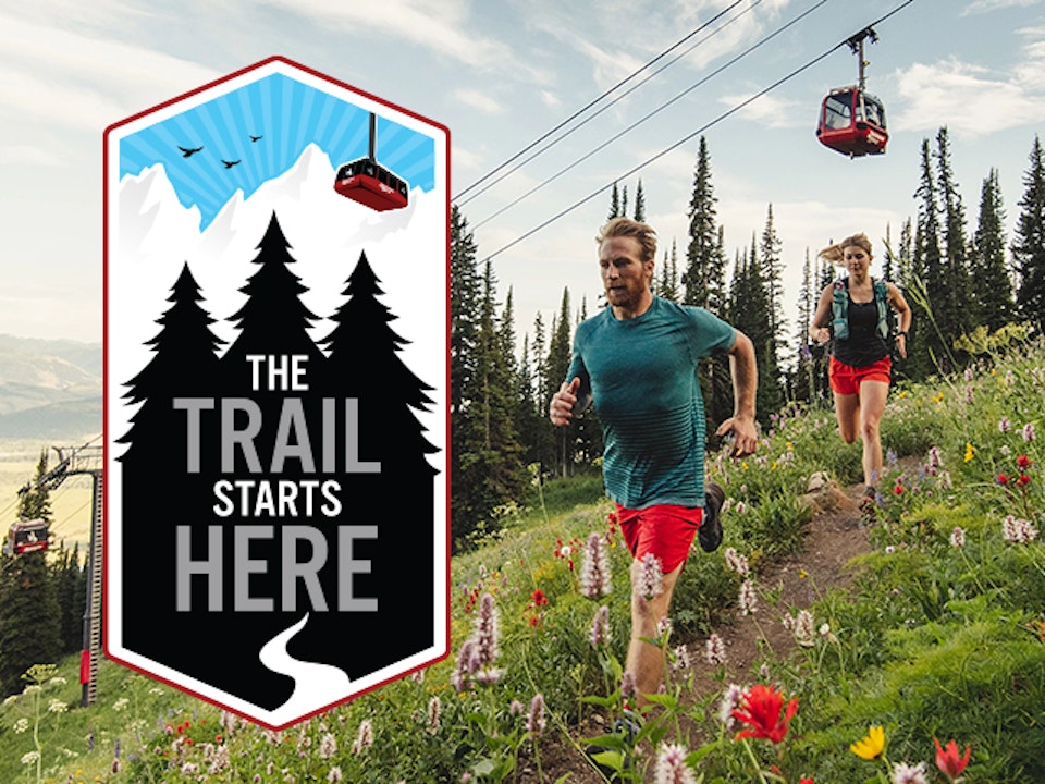 Man and woman trail running with The Trail Starts Here logo