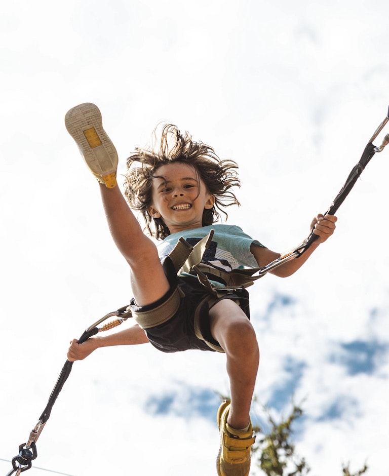 boy kicking his leg out while jumping on bungee trampoline