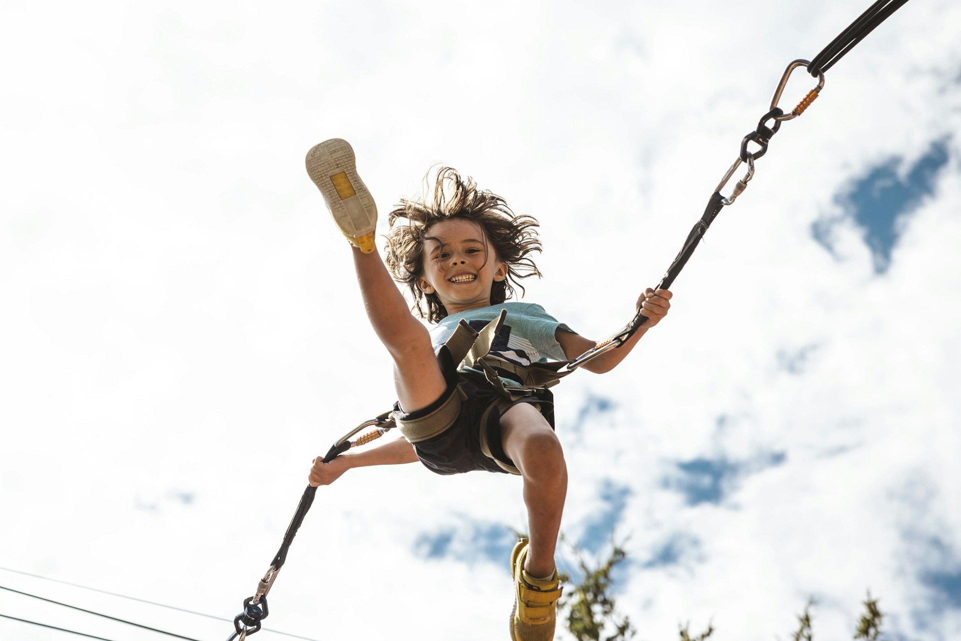 boy kicking his leg out while jumping on bungee trampoline