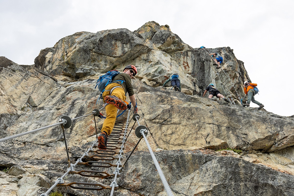 man walking up ladder on the Via Ferrata with rest of group ahead of him