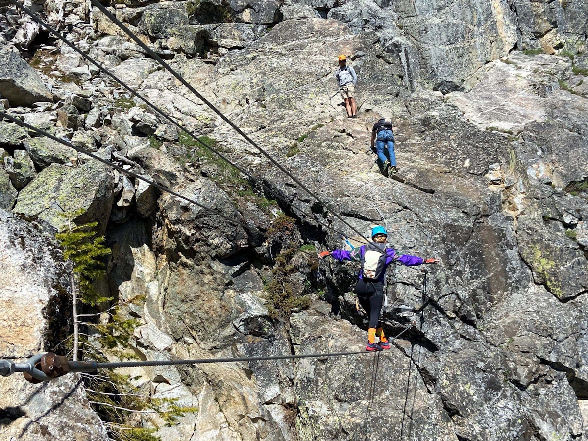 Woman walking across a wire on the Via Ferrata