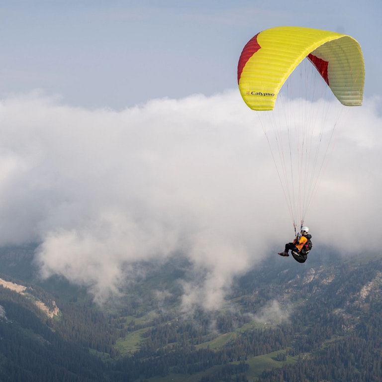 Person paragliding above the clouds