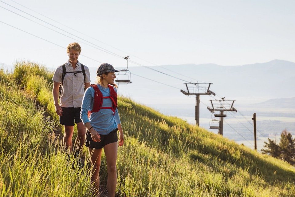 Hikers on a grassy trail with chairlift in background
