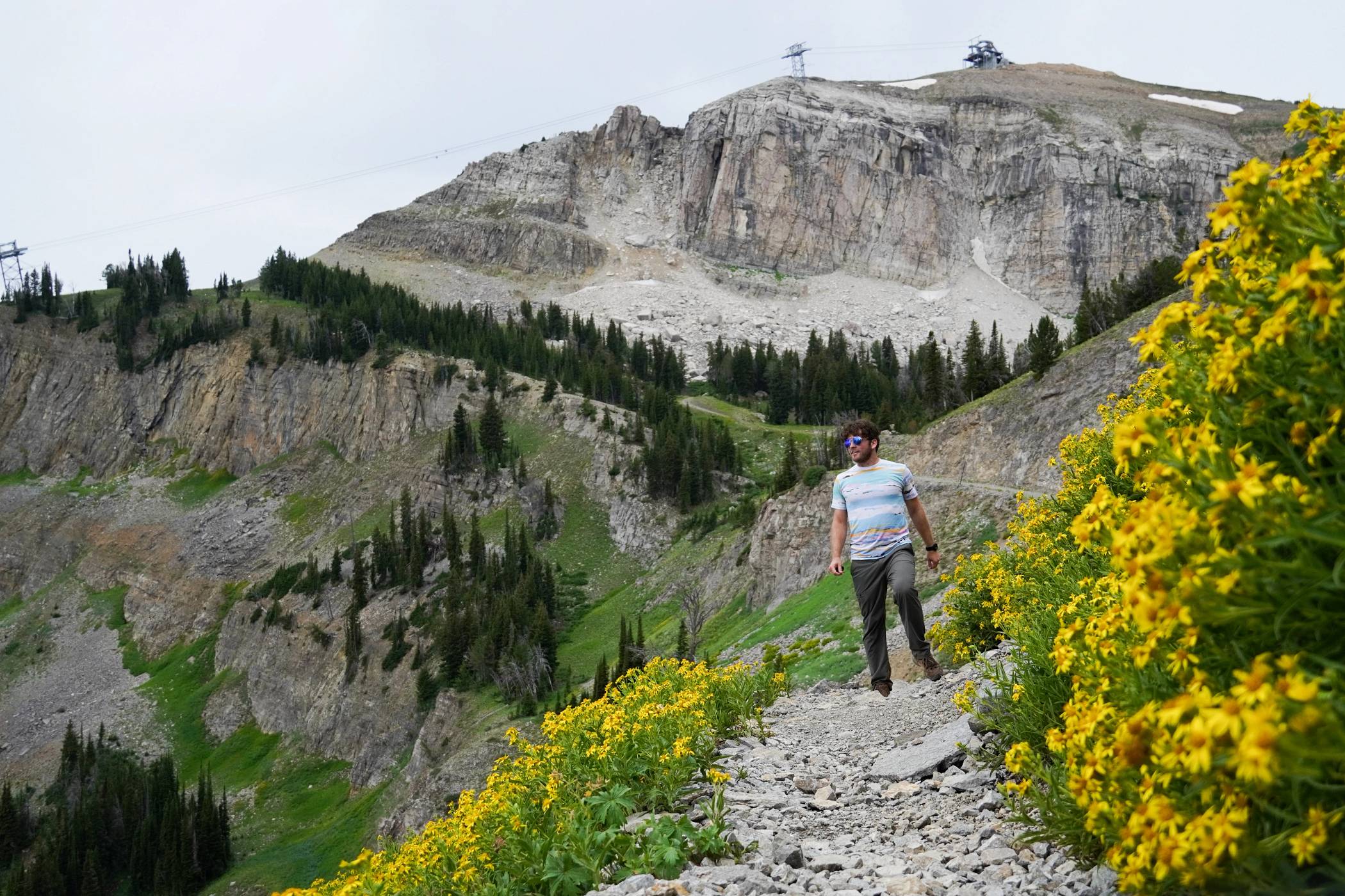 Man walking along the Cirque Trail surrounded by flowers