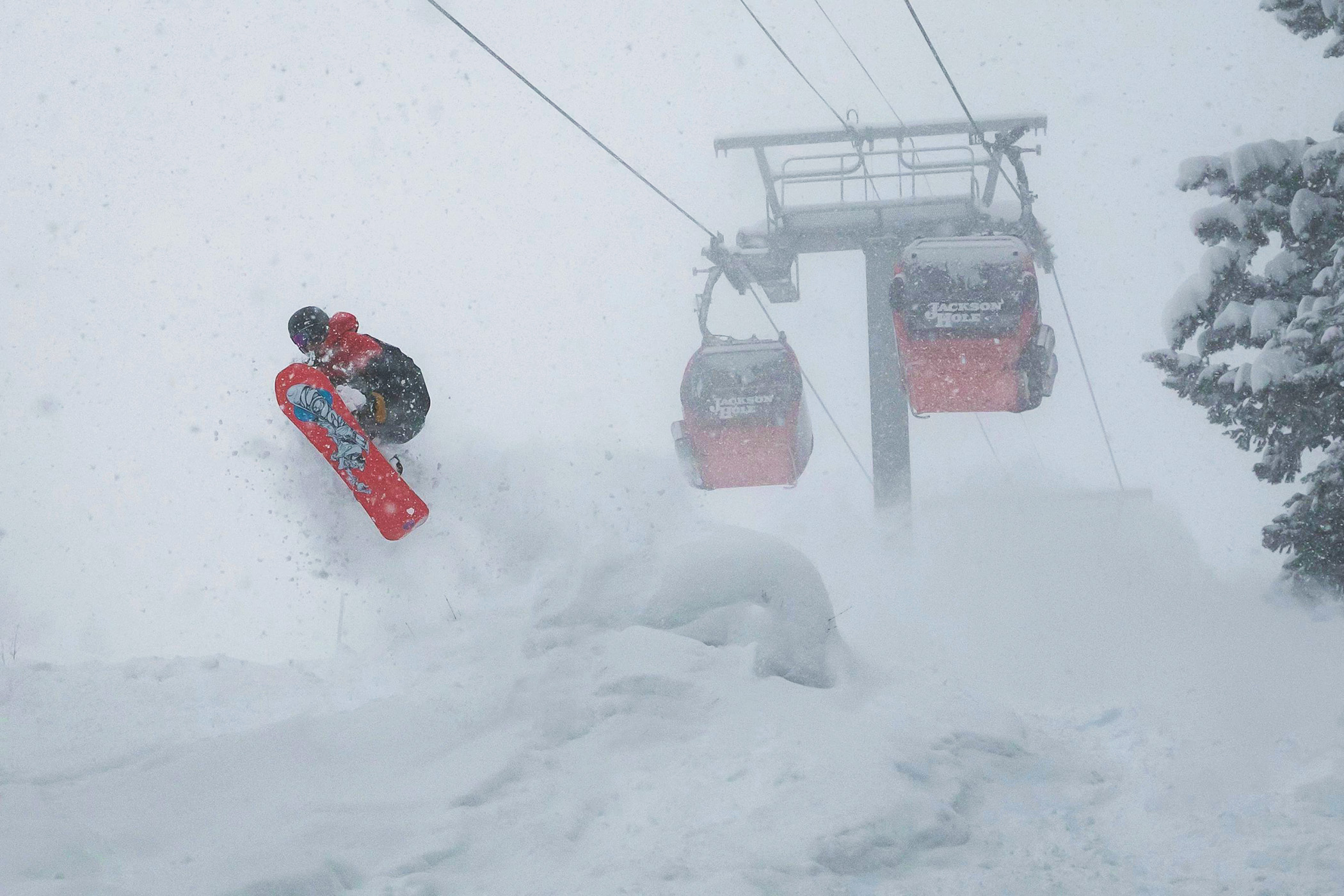 Snowboarder jumping off a rock covered in powder