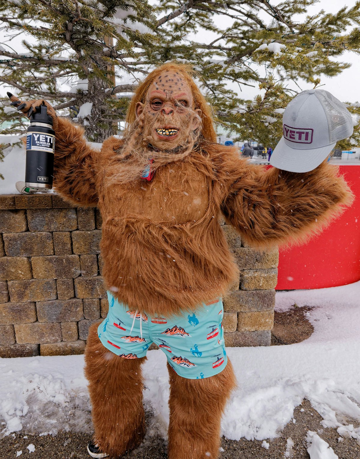 Person in a yeti costume holding a YETI mug and hat