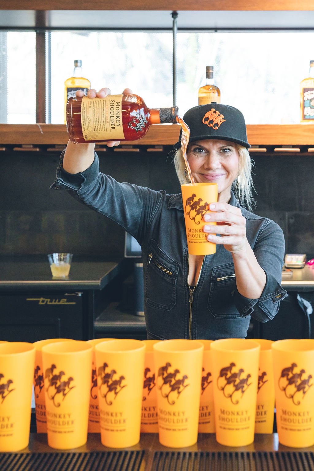 woman pouring Monkey Shoulder whiskey into a cup