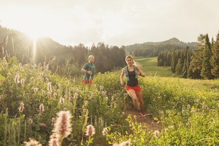 Two people trail running through wildflowers