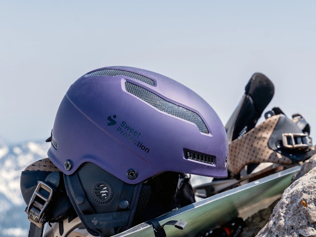 Purple Sweet Protection helmet sitting on a snowboard
