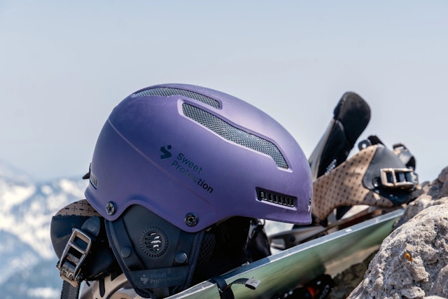 Purple Sweet Protection helmet sitting on a snowboard