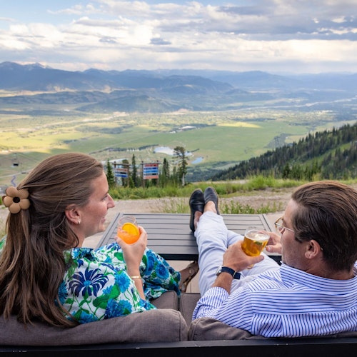 Man and woman enjoying the view from the Deck at Piste with drinks