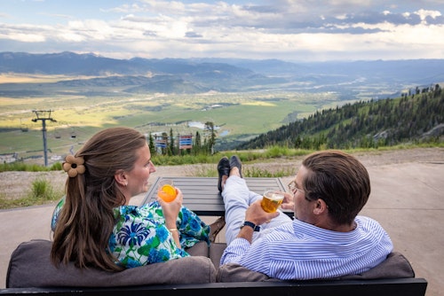 Man and woman enjoying the view from the Deck at Piste with drinks