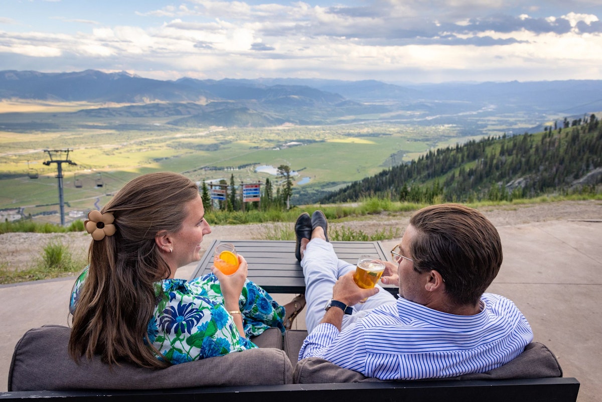 Man and woman enjoying the view from the Deck at Piste with drinks
