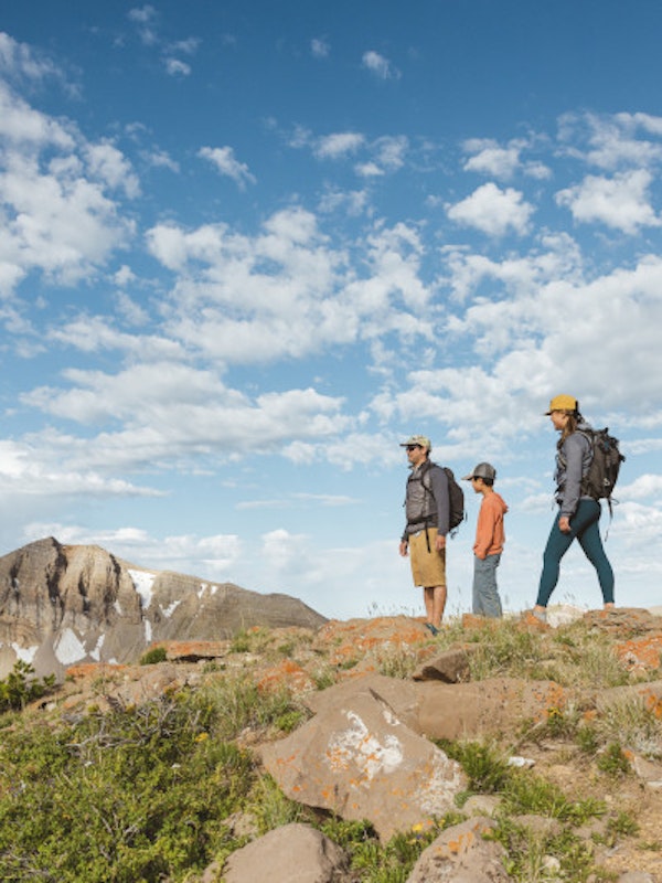 Three people hiking with Cody Peak in the background