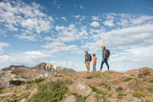 Three people hiking with Cody Peak in the background