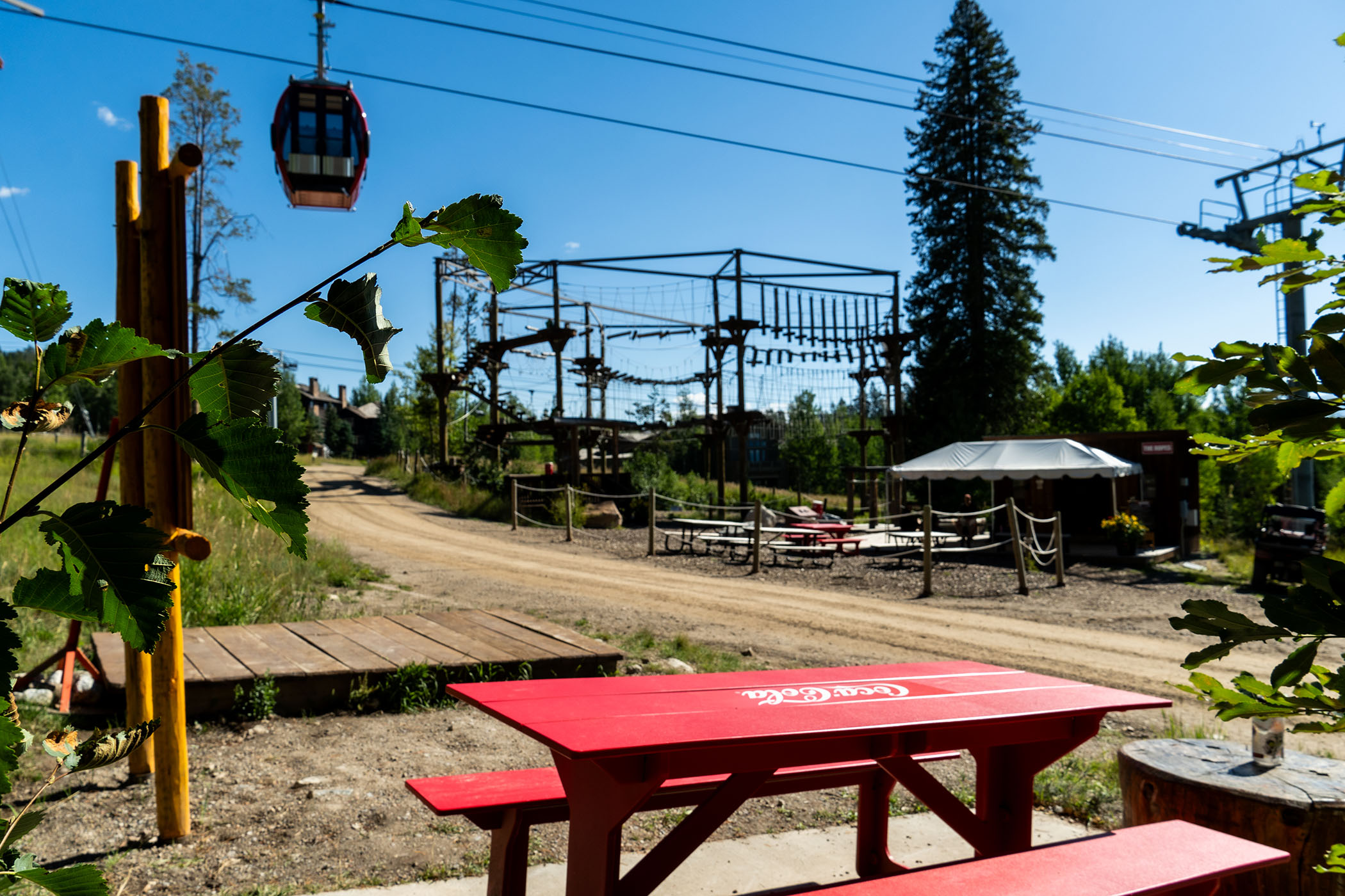 A Coca-Cola picnic bench with the Aerial Ropes Course in the background