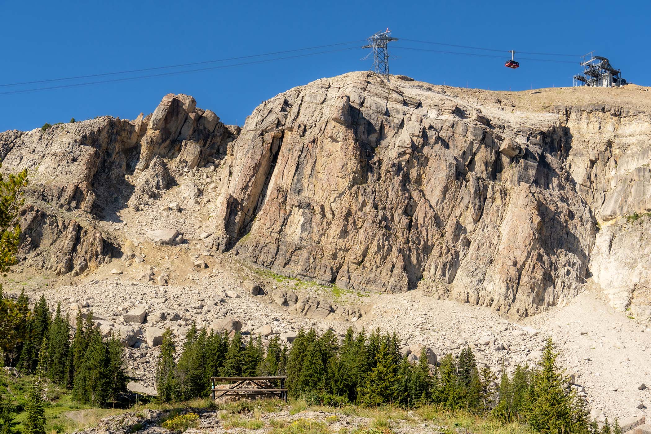A picnic bench along the Cirque trail with the Tram flying in the air in the background