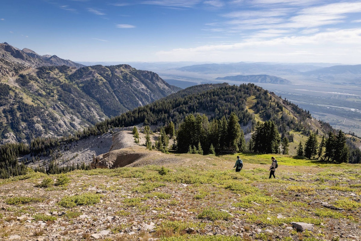 Two hikers with lush mountains in the background