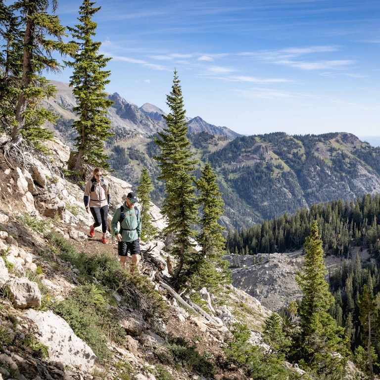Two hikers on the North Ridge Trail with mountains in the background