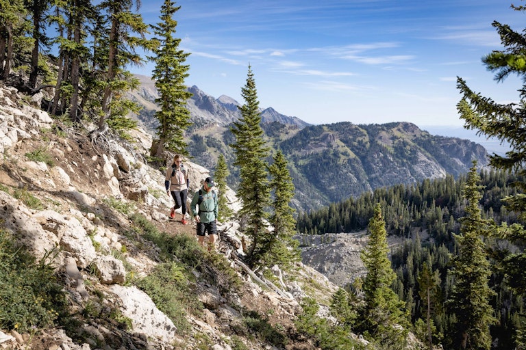 Two hikers on the North Ridge Trail with mountains in the background