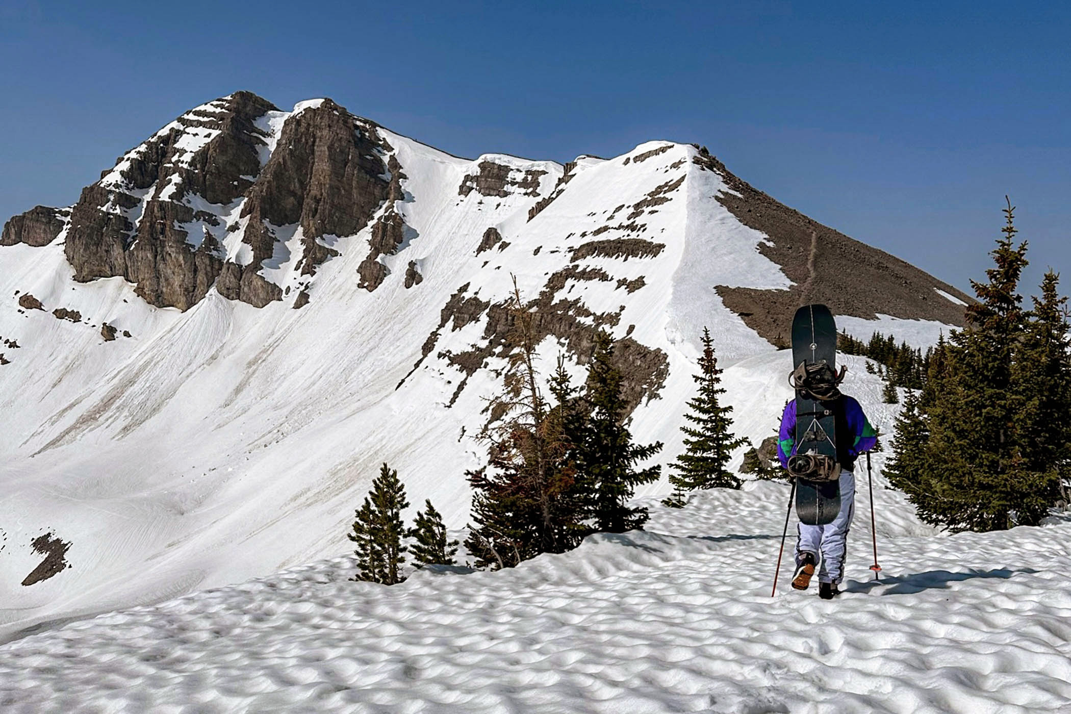 A snowboarder hiking to Cody Peak