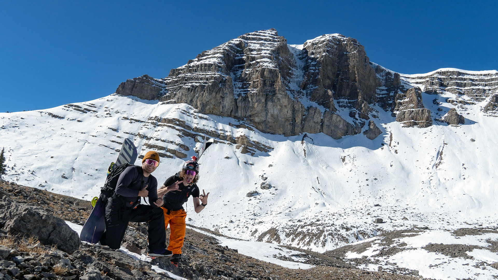 A skier and snowboarder posing in front of Cody Peak