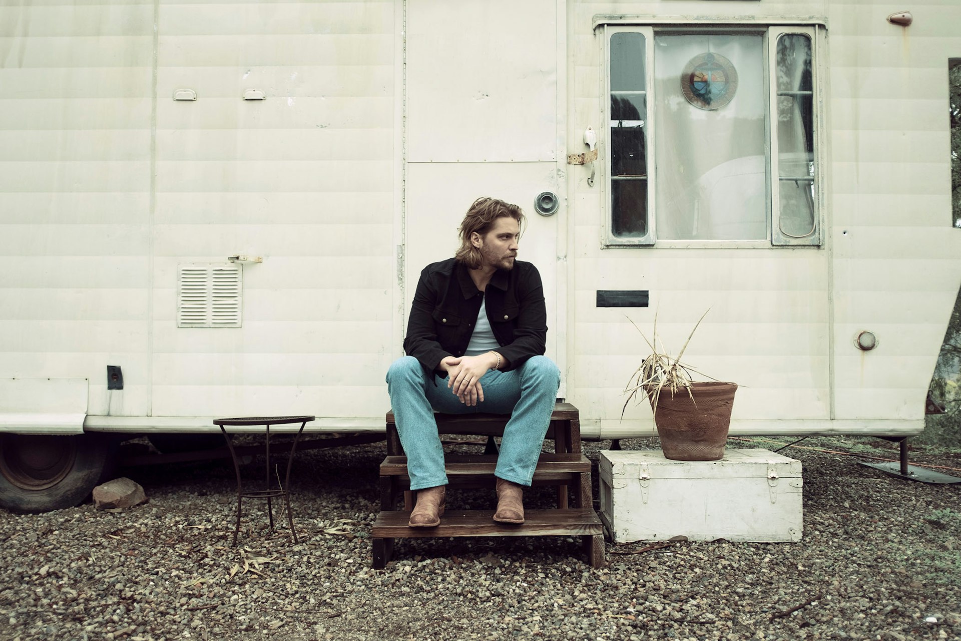 Luke Grimes sitting on stairs of mobile home