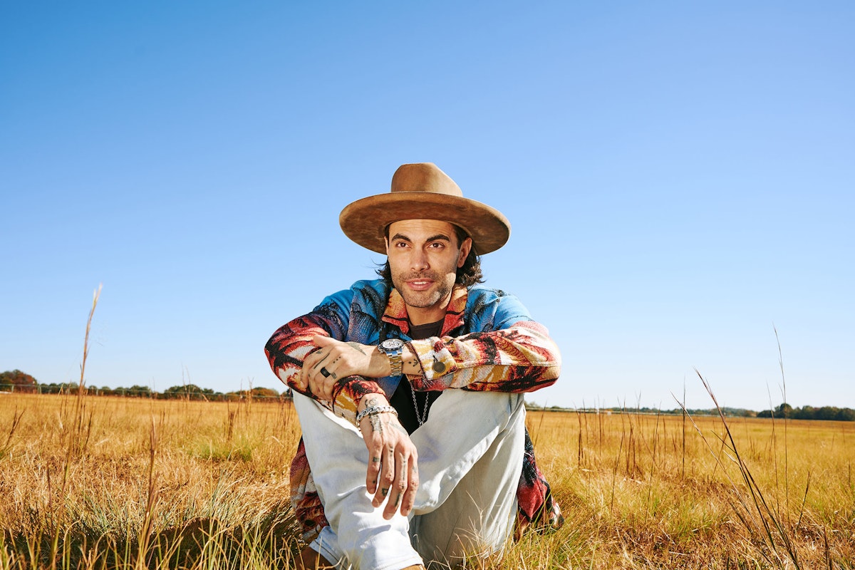 Niko Moon sitting in a field