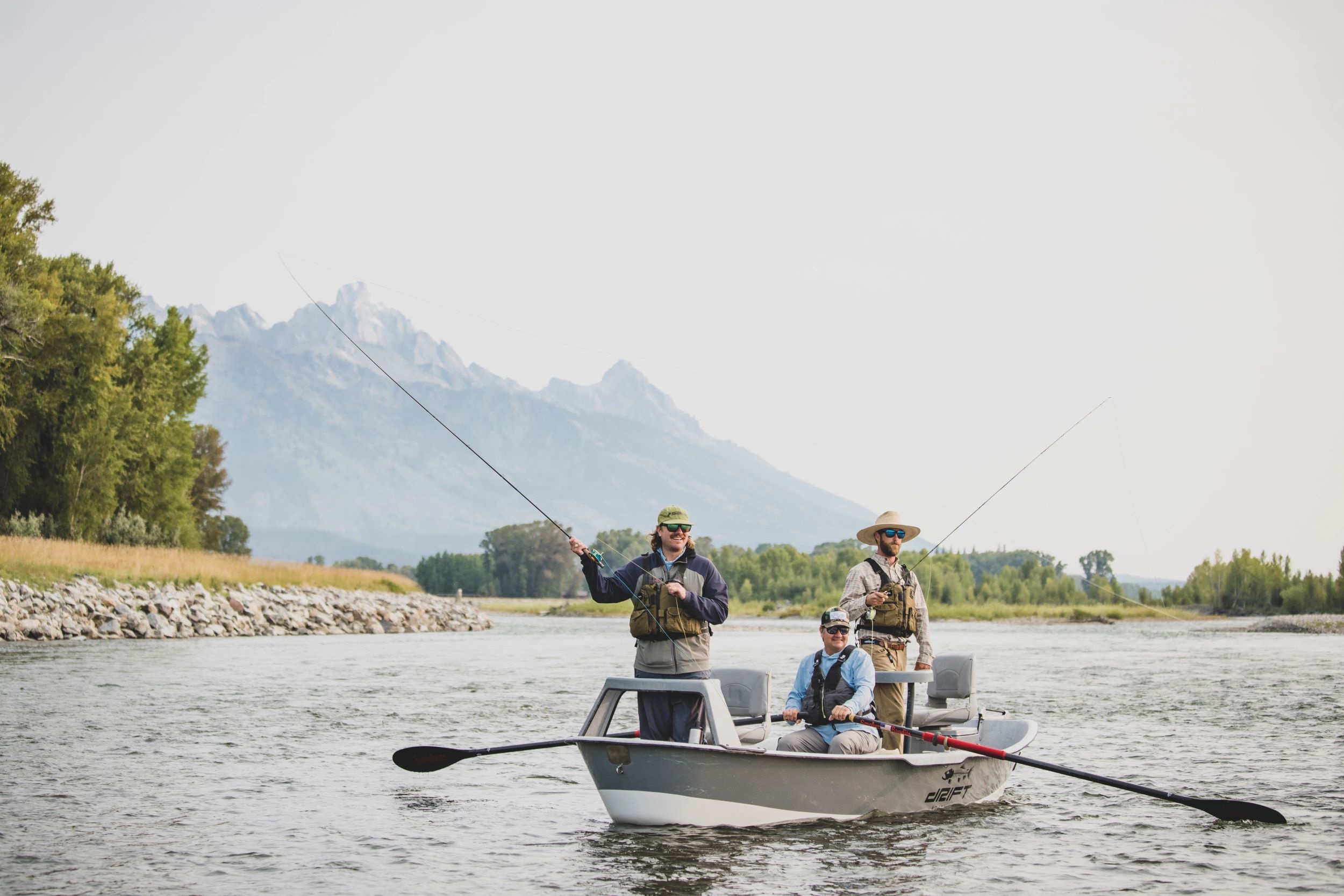 People fishing from a boat with Tetons in background