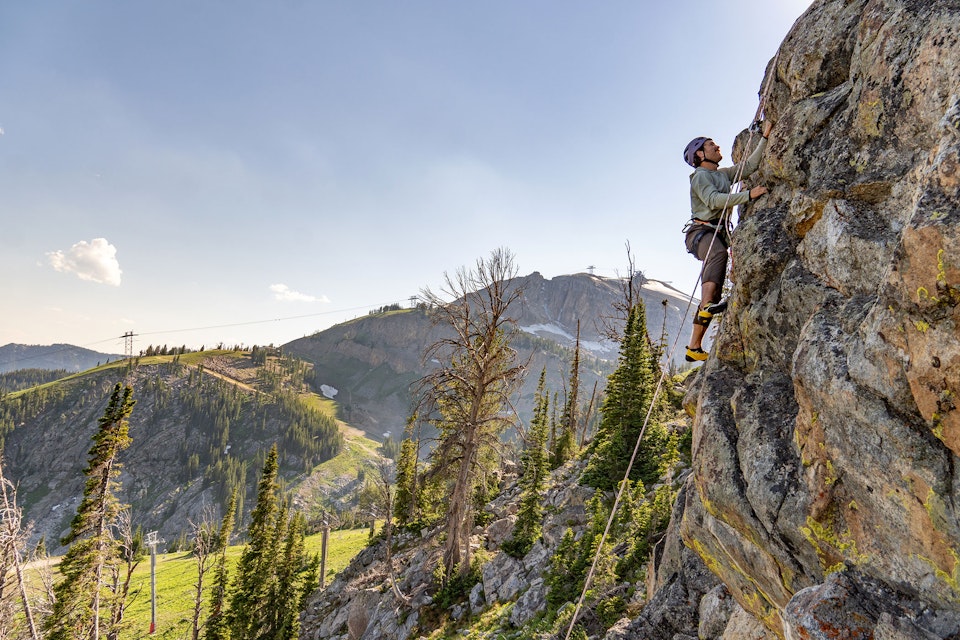 Man rock climbing with Rendezvous Peak in background