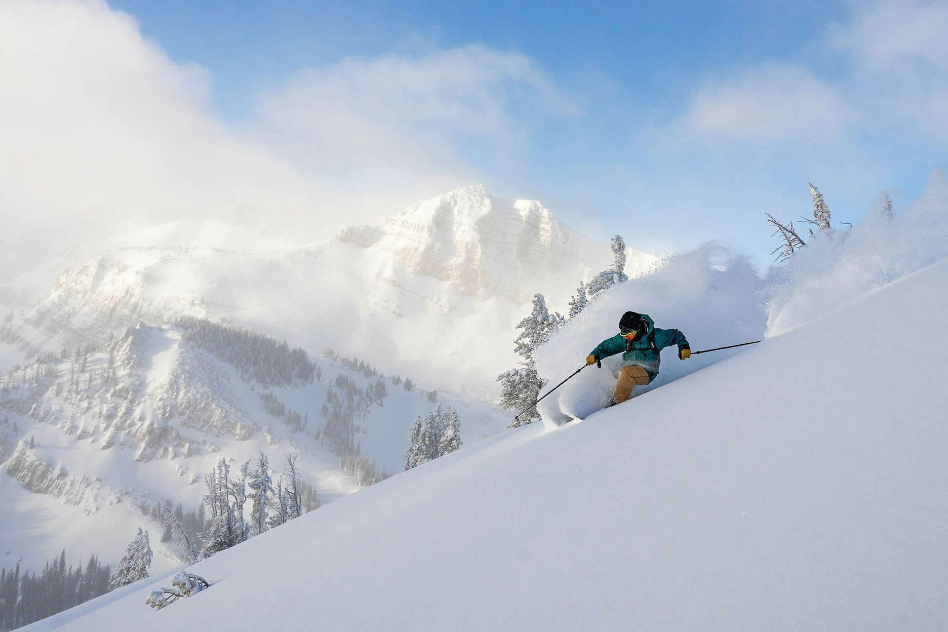 Skiier in power with cody peak in background