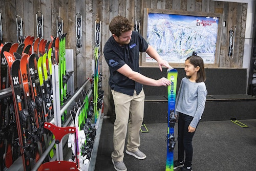 Rental employee picking out a ski for a kid