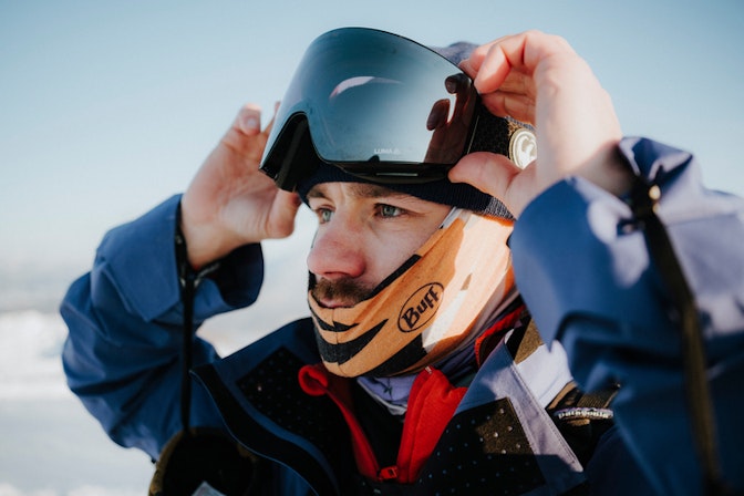 Skier putting on goggles wearing a buff
