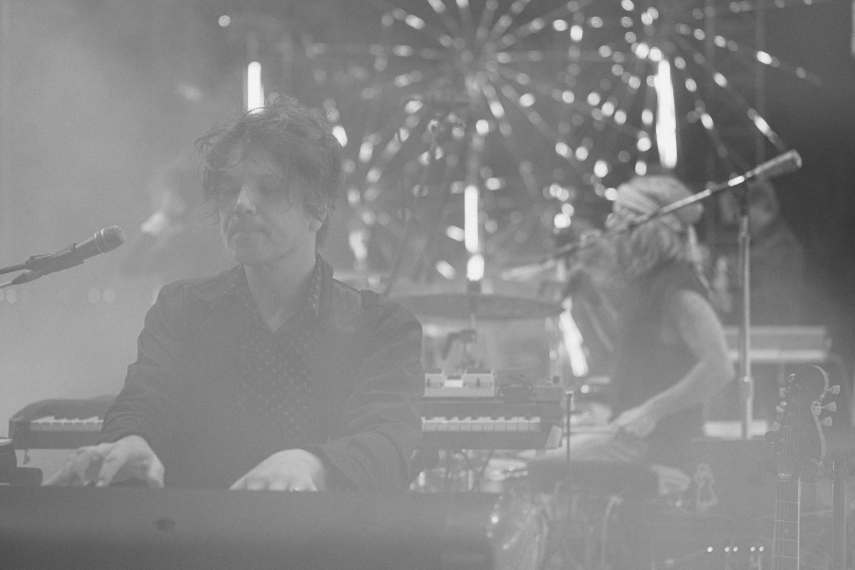 Flaming Lips pianist, drummer in the background, performing live. black and white photo.