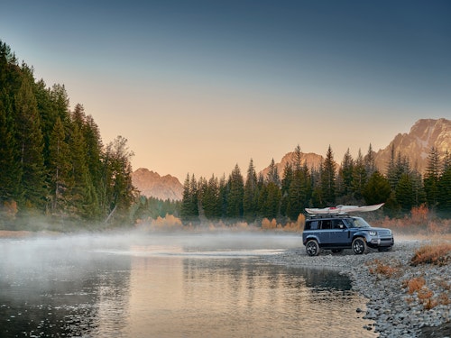 Defender with canoe on top by lake