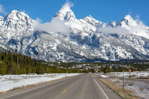 Teton mountain range with snow on it and a road in front