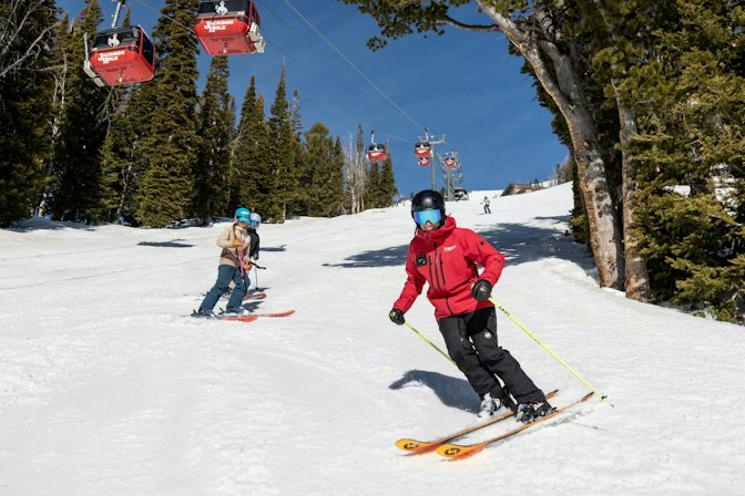 Smiling ski instructor with students under the gondola