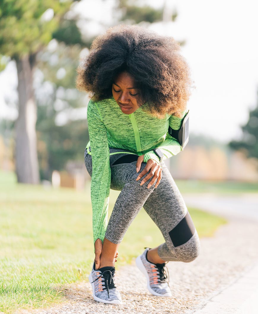 Female jogger holding ankle in pain