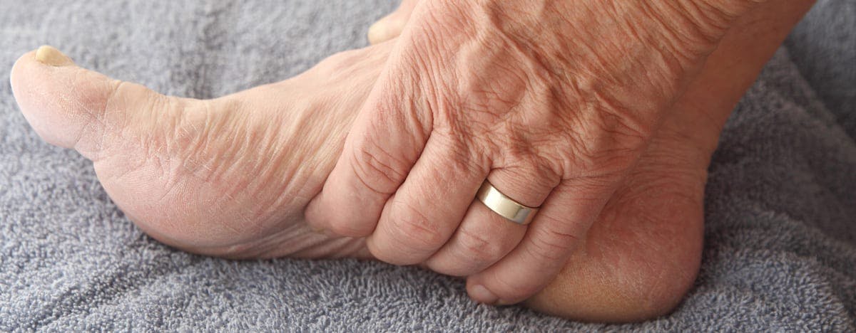 an elderly person grasping the bottom of their foot