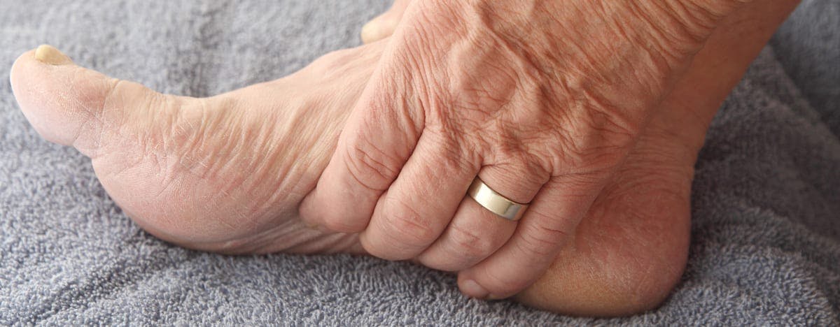 an elderly person grasping the bottom of their foot
