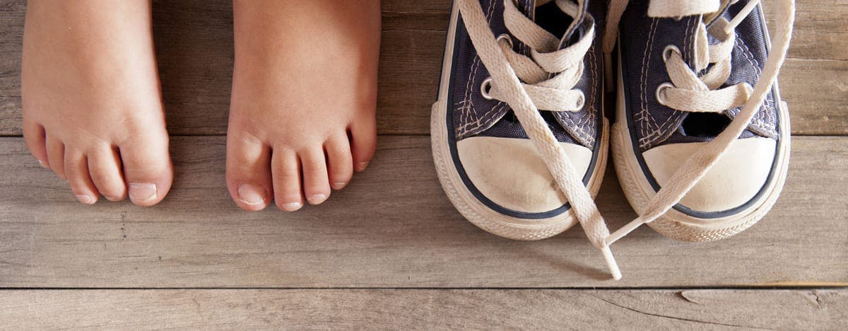 and image of child's feet next to a pair of sneakers