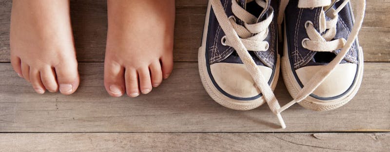 and image of child's feet next to a pair of sneakers