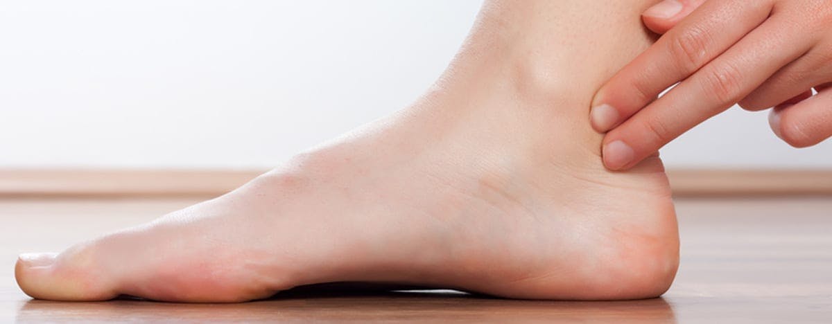 a close up of a foot and someone touching the back of the ankle