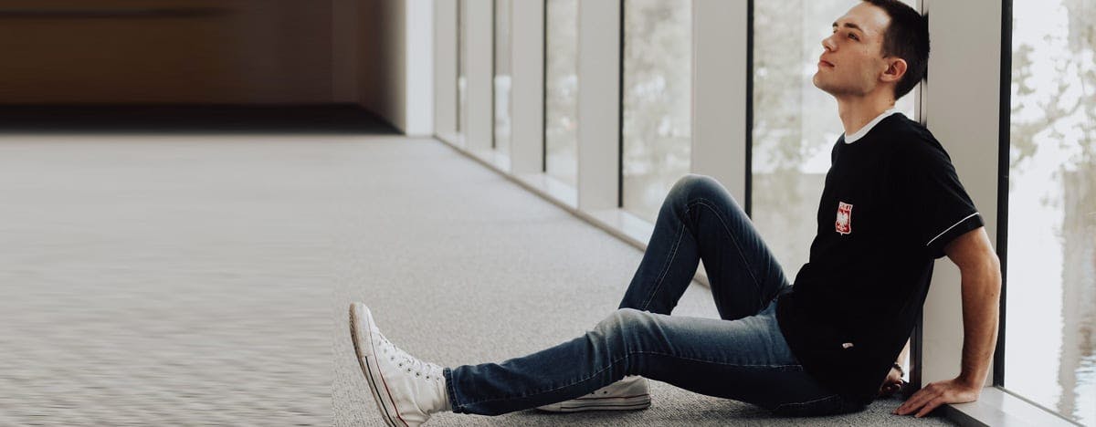 an image of a man sitting on the floor with his back against a window