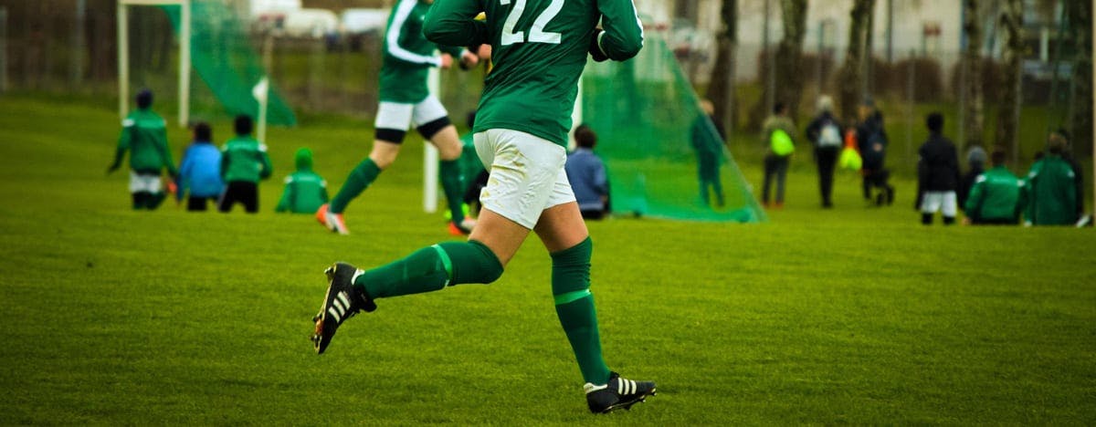 an image of a soccer player running on the field in a green and white uniform