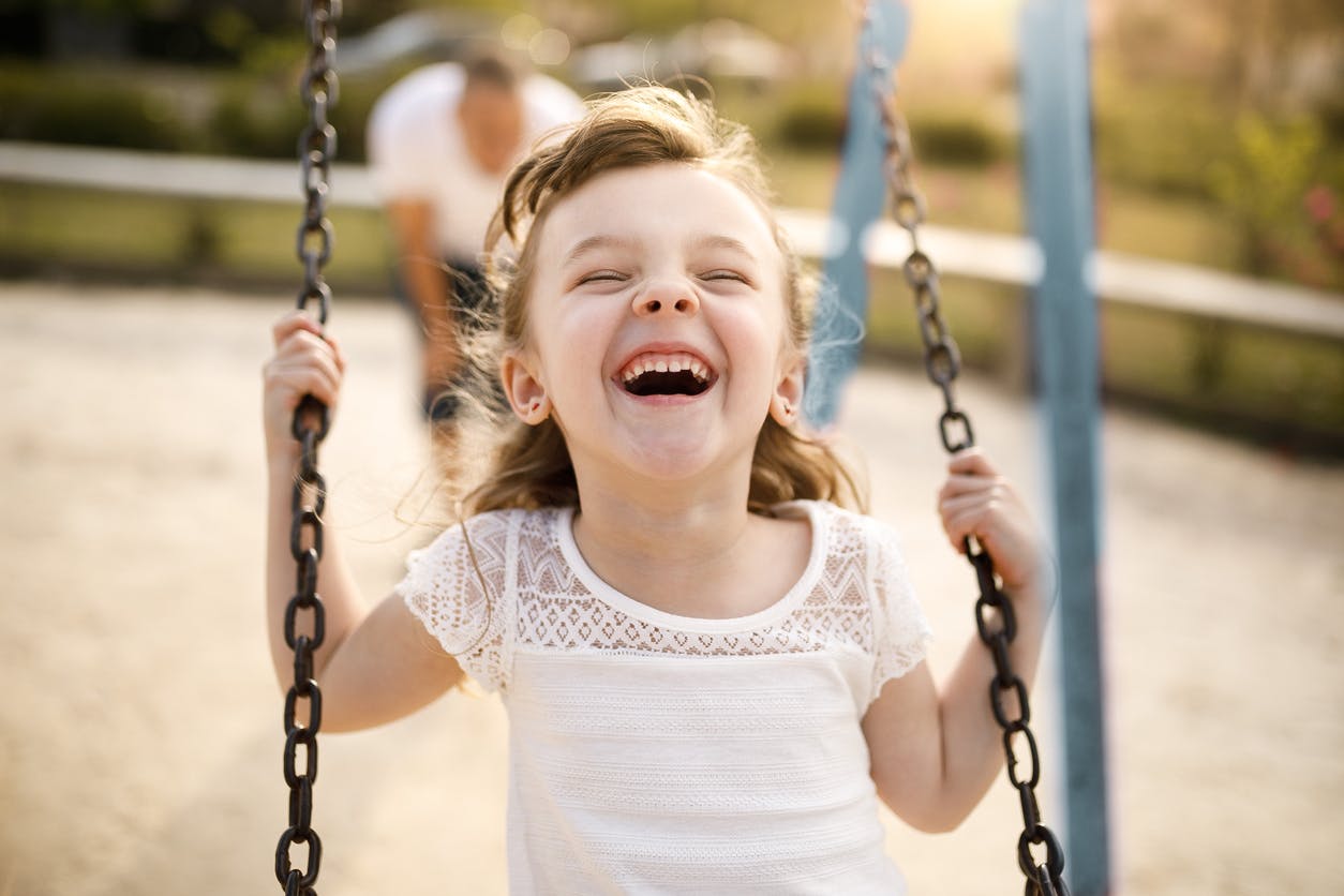 Little girl laughing on a swing