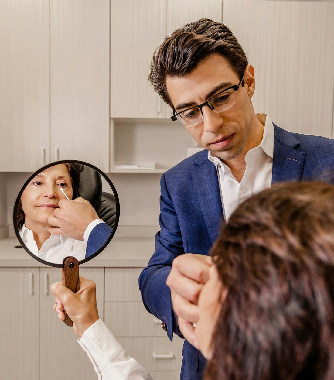dr fisher touching a patients face with a q tip while she looks in the mirror