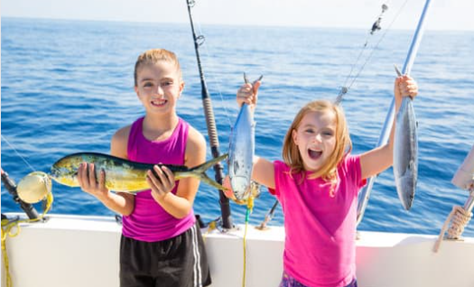 Two girls holding up fish.