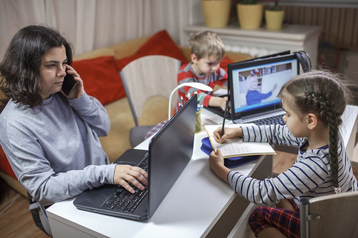 Mère en télétravail entourée de ses deux enfants